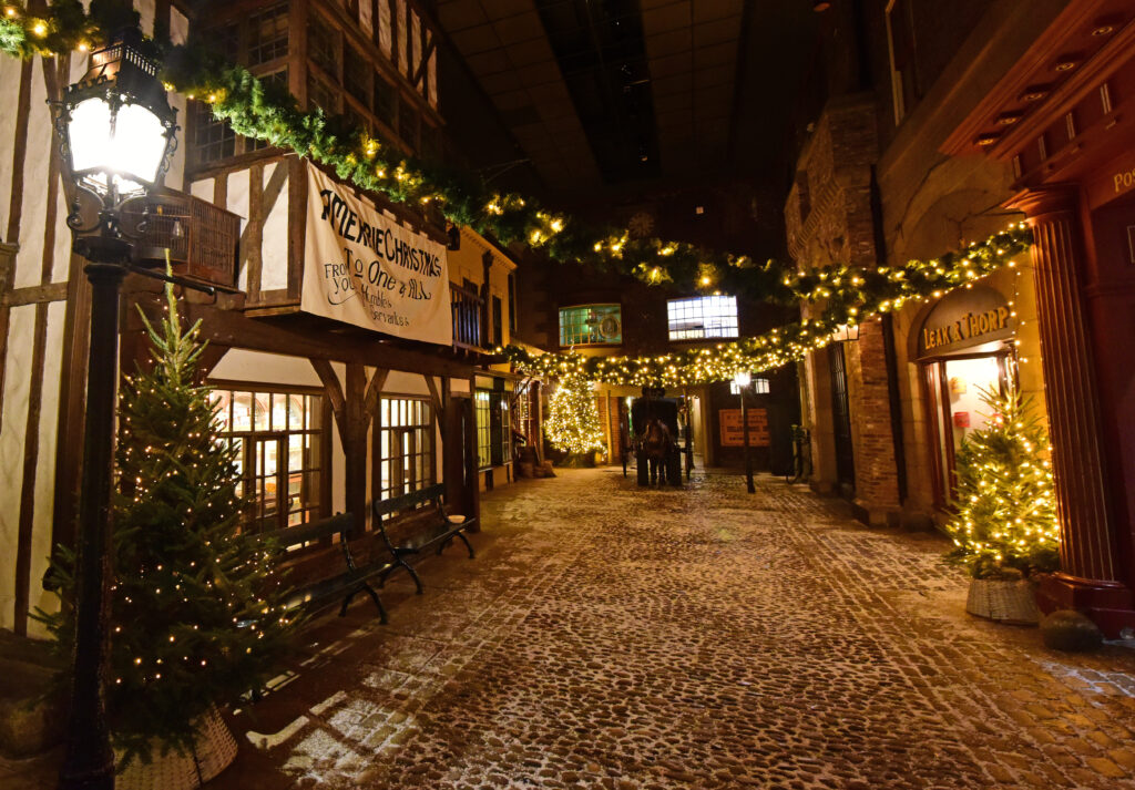 Festive Victorian Street at York Castle Museum with decorated shopfronts, Christmas trees, garlands and visitors enjoying the seasonal atmosphere